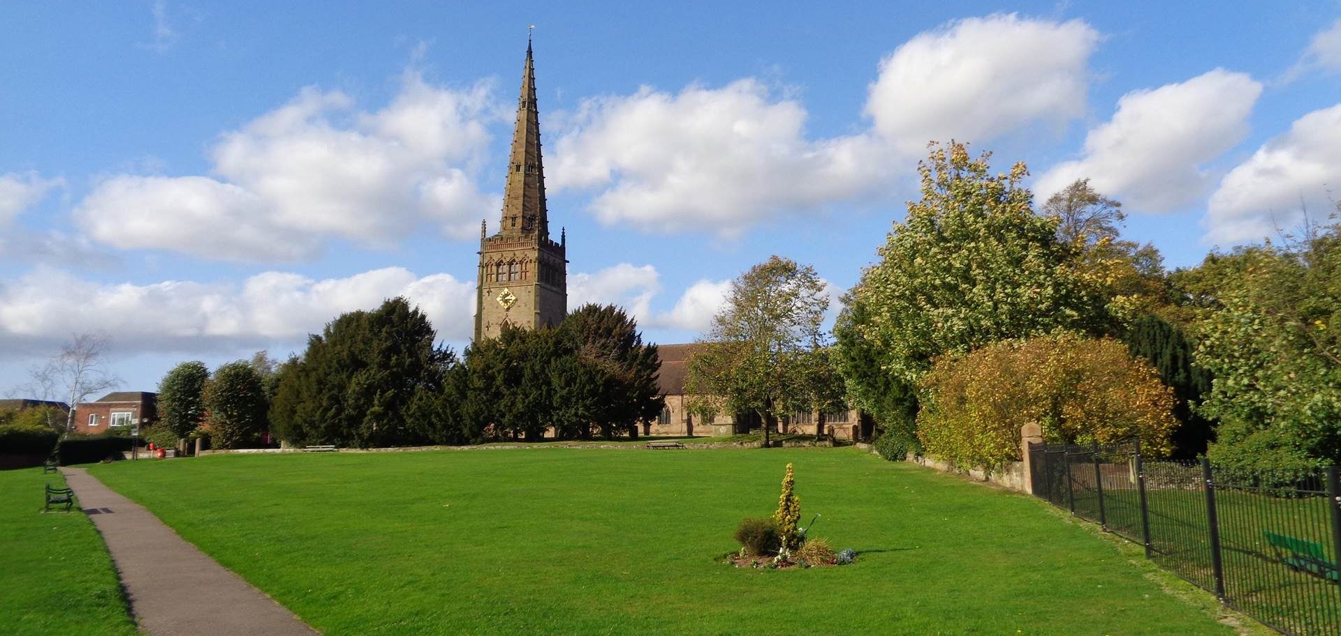 Church tower and green parkland, clear sky.