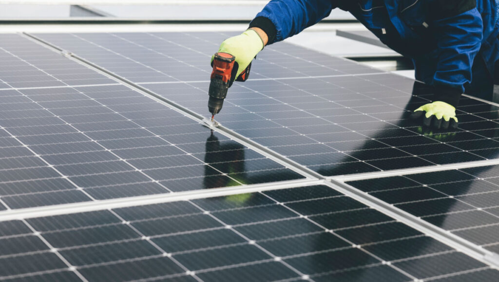 Technician installing solar panels with electric screwdriver