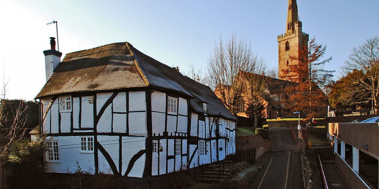 Historic half-timbered house with church in background.