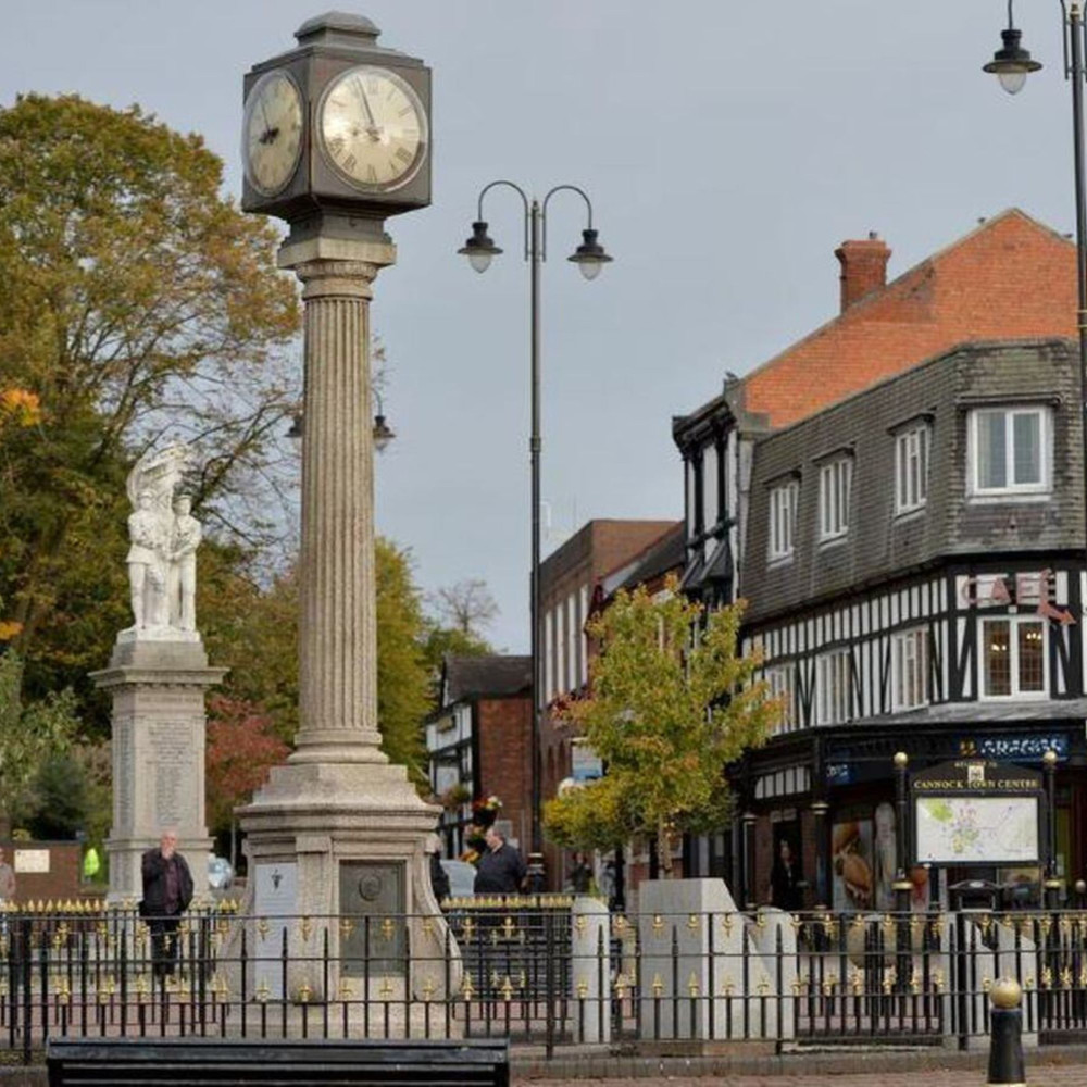 Historic town centre with clock and statues.